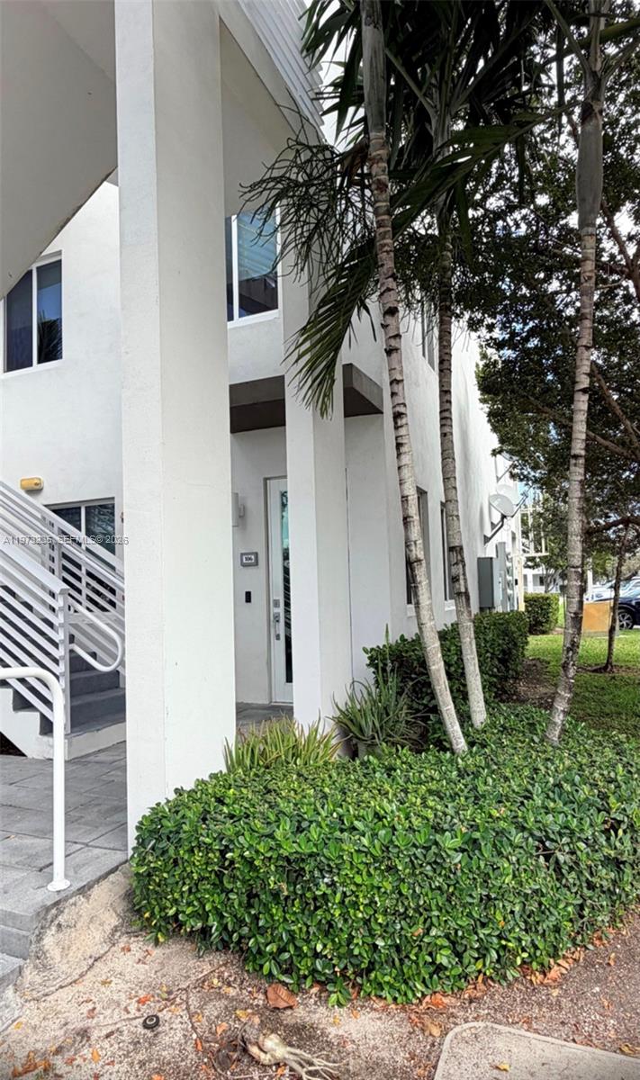 A white multi-story building exterior features a staircase, palm trees, and a landscaped garden — 6401 NW 103rd Pl # 106, Doral FL 33178, DORAL, FL