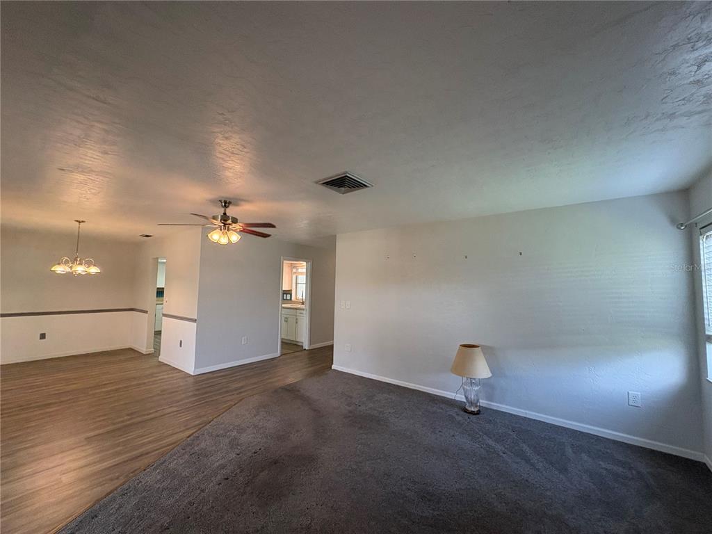 A living room features gray carpet, a ceiling fan, and an adjacent dining area — 3276 BRUNSWICK LANE UNIT 705, SARASOTA, FL