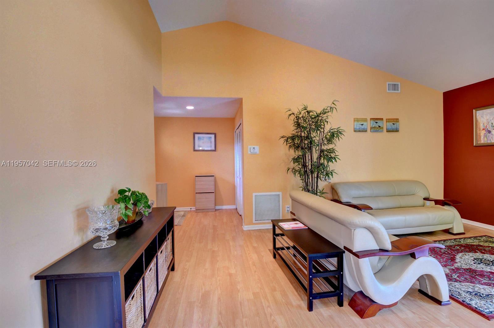 A living room features light wood floors, vaulted ceilings, and a beige leather sofa — 6027 Parkwalk Dr # 0, Boynton Beach FL 33472, BOYNTON BEACH, FL