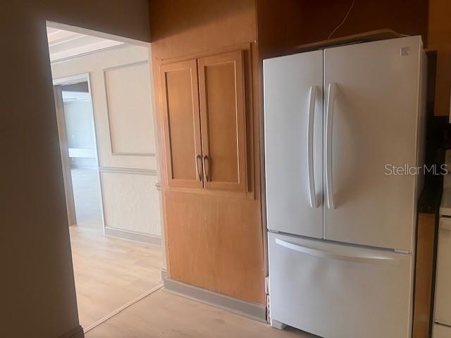A white refrigerator stands next to wooden cabinets in a kitchen with light flooring — 3717 46TH AVENUE S UNIT 11, ST PETERSBURG, FL