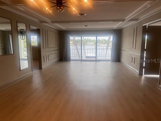 A spacious living room features light wood-look flooring, wall molding, and sliding glass doors overlooking water — 3717 46TH AVENUE S UNIT 11, ST PETERSBURG, FL