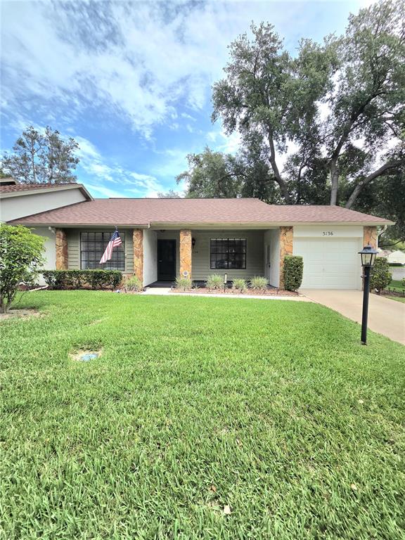 A single-story house features a brown shingled roof, stone accents, and a front lawn — 3136 CLOISTER COURT, SPRING HILL, FL