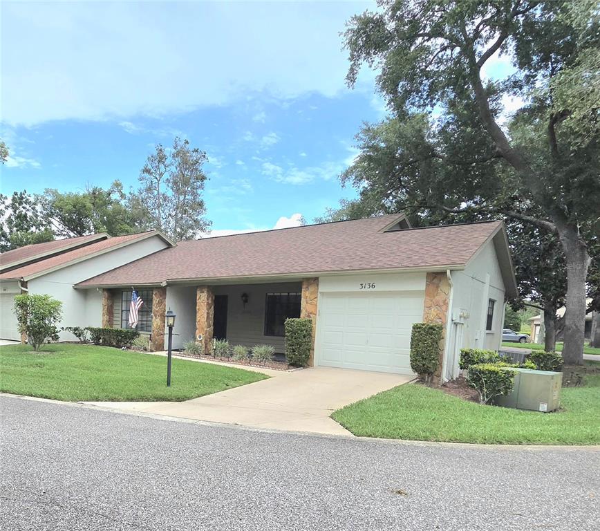 A single-story house with a tan exterior, stone accents, and a white garage door — 3136 CLOISTER COURT, SPRING HILL, FL