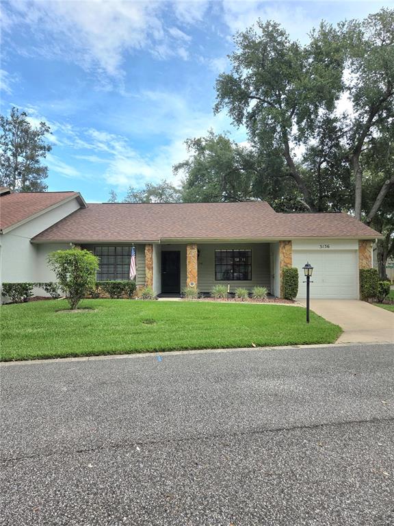 A single-story house with a brown shingled roof, stone accents, and a one-car garage — 3136 CLOISTER COURT, SPRING HILL, FL