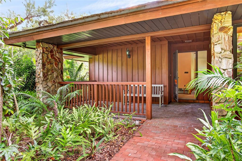 A brick walkway leads to a covered porch with wood siding and stone pillars — 3460/3480 RIVER RUN LANE, FORT MYERS, FL