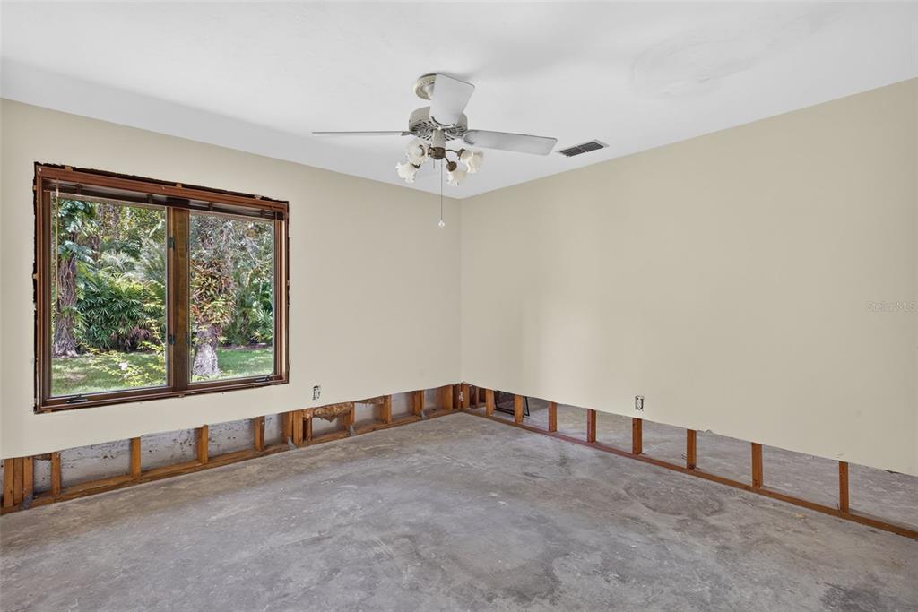 An empty room with exposed wall studs, a concrete floor, and a ceiling fan — 3460/3480 RIVER RUN LANE, FORT MYERS, FL