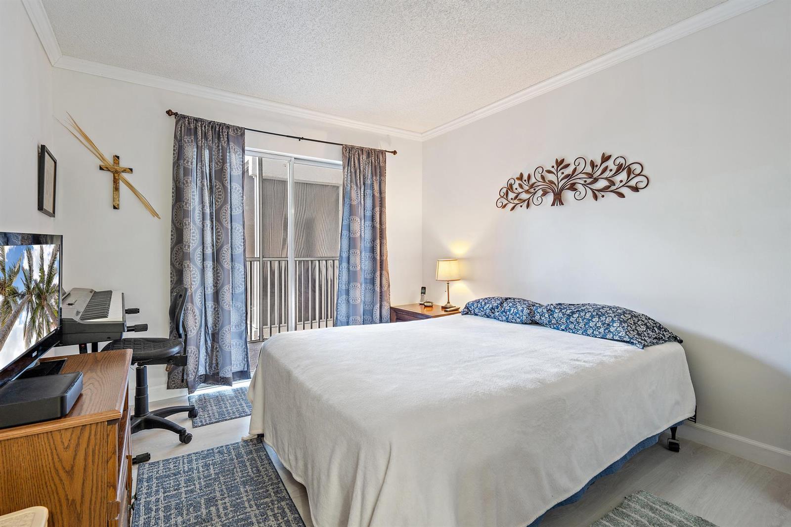 A bedroom features a bed, a desk with a keyboard, and a sliding glass door — 1516 S Lakeside Drive # 207, FL 33460, FL