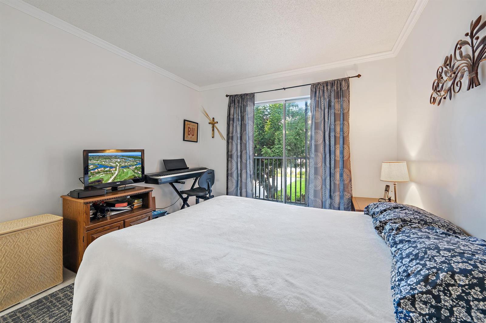 A bedroom features a bed, a television on a wooden stand, and a sliding glass door — 1516 S Lakeside Drive # 207, FL 33460, FL