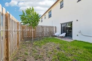 A small backyard features a patch of grass, a wooden fence, and a sliding glass door — 23080 SW 99th Ct, Cutler Bay FL 33190, CUTLER BAY, FL