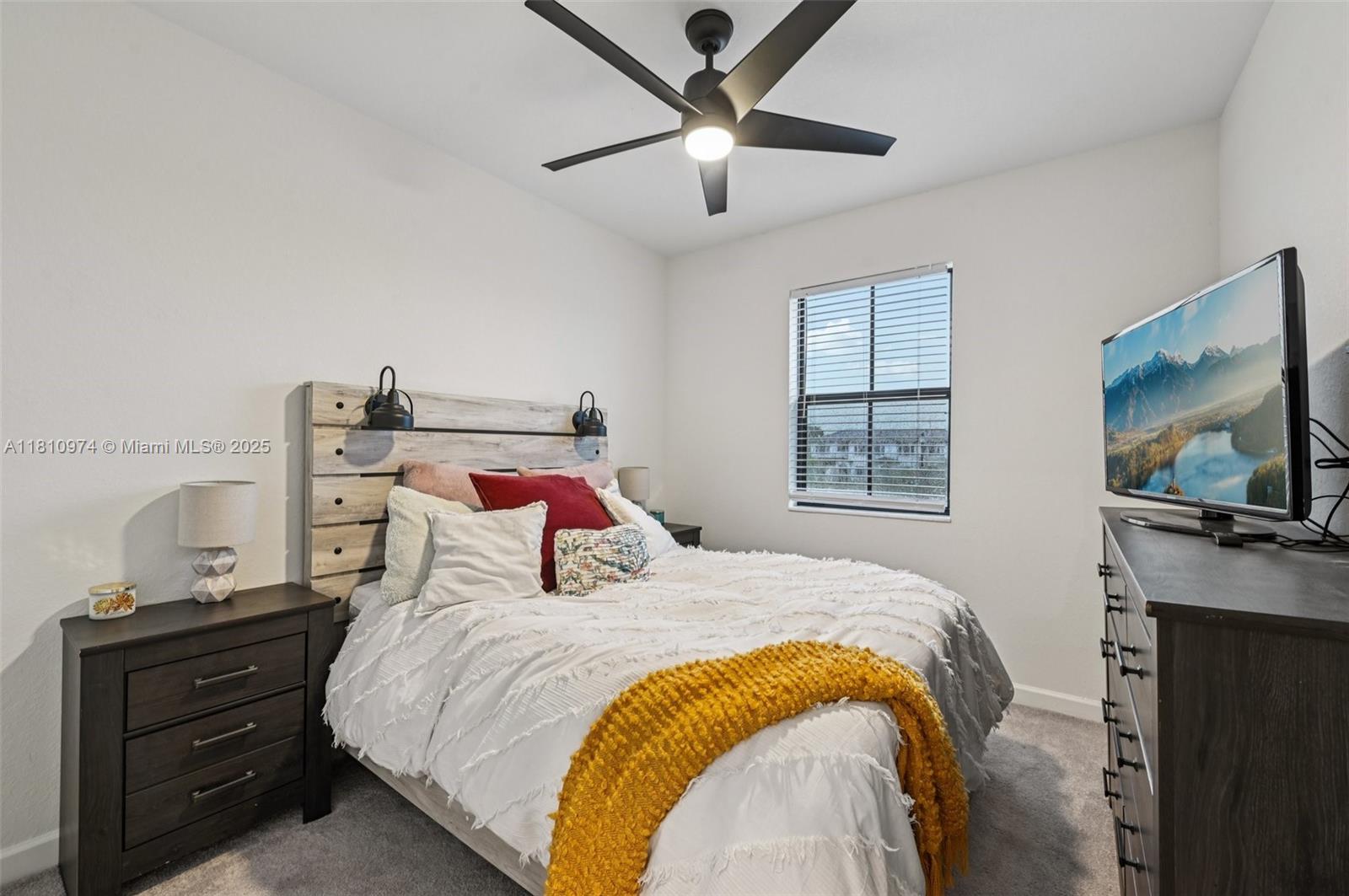A bedroom features a bed with a wooden headboard, a ceiling fan, and a television — 23080 SW 99th Ct, Cutler Bay FL 33190, CUTLER BAY, FL