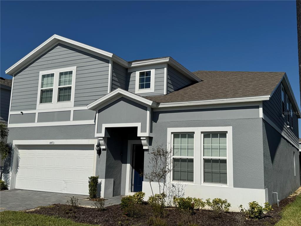 A two-story house with gray siding, a white garage door, and a small front porch — 4473 KAIPO ROAD, DAVENPORT, FL