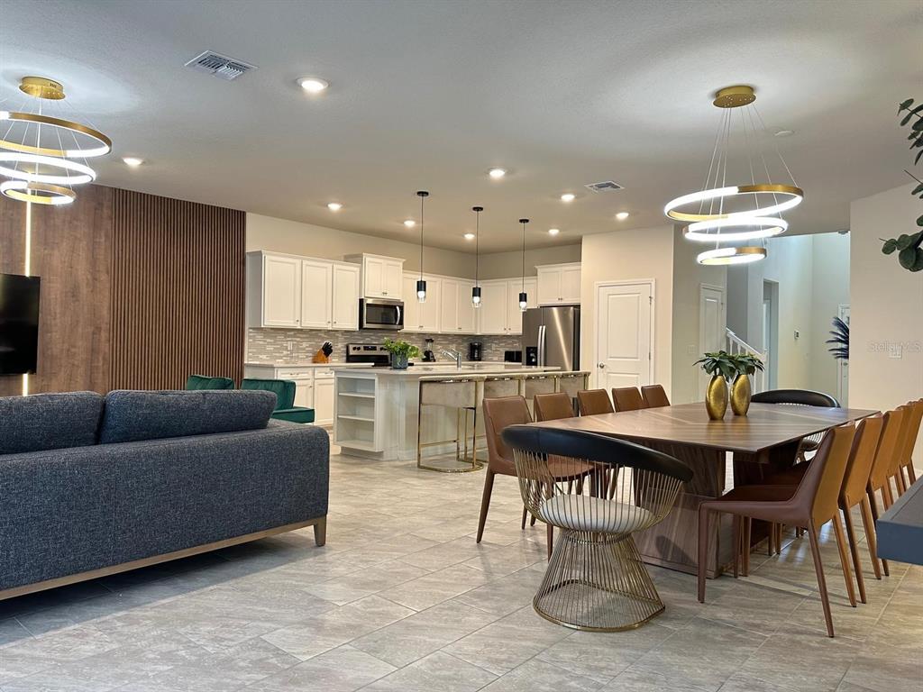 An open-concept kitchen and dining area features white cabinetry, a central island, and modern lighting — 4473 KAIPO ROAD, DAVENPORT, FL