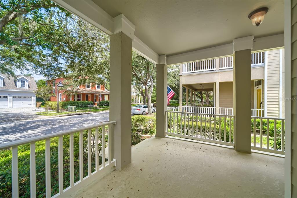 A covered porch with white railings overlooks a street and neighboring houses — 3305 BRACKEN FERN DRIVE, HARMONY, FL