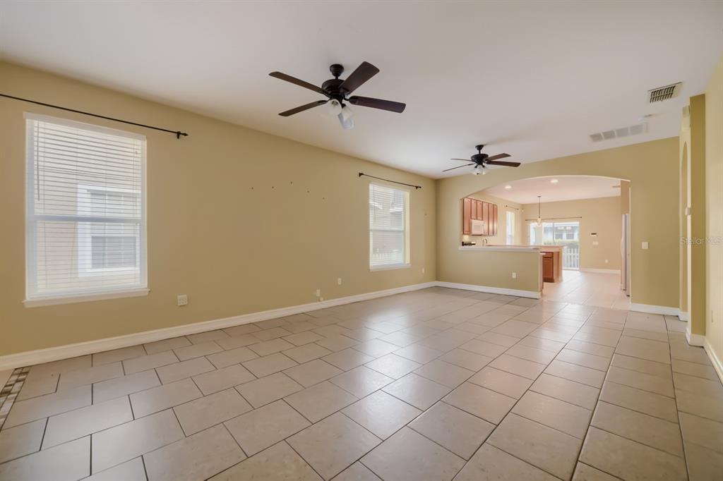 An open-concept living area features light-colored tile flooring, two ceiling fans, and arched entryways — 3305 BRACKEN FERN DRIVE, HARMONY, FL