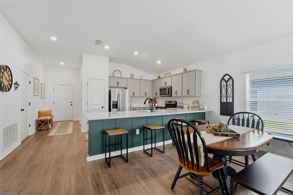 A kitchen with gray cabinets and stainless steel appliances opens to a living area — 15335 COPPER LOOP, BROOKSVILLE, FL
