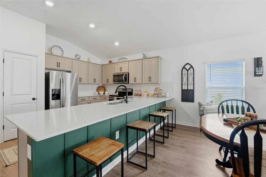 A kitchen with gray cabinets, a green island, and an adjacent dining area — 15335 COPPER LOOP, BROOKSVILLE, FL