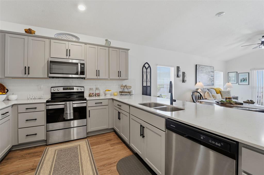A kitchen features a green-paneled island with bar stools, white countertops, and light-colored cabinetry — 15335 COPPER LOOP, BROOKSVILLE, FL