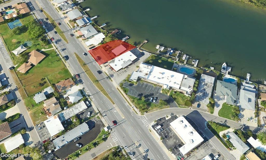 This aerial view shows a waterfront property with a highlighted building and boat docks — 18207 GULF BOULEVARD, REDINGTON SHORES, FL