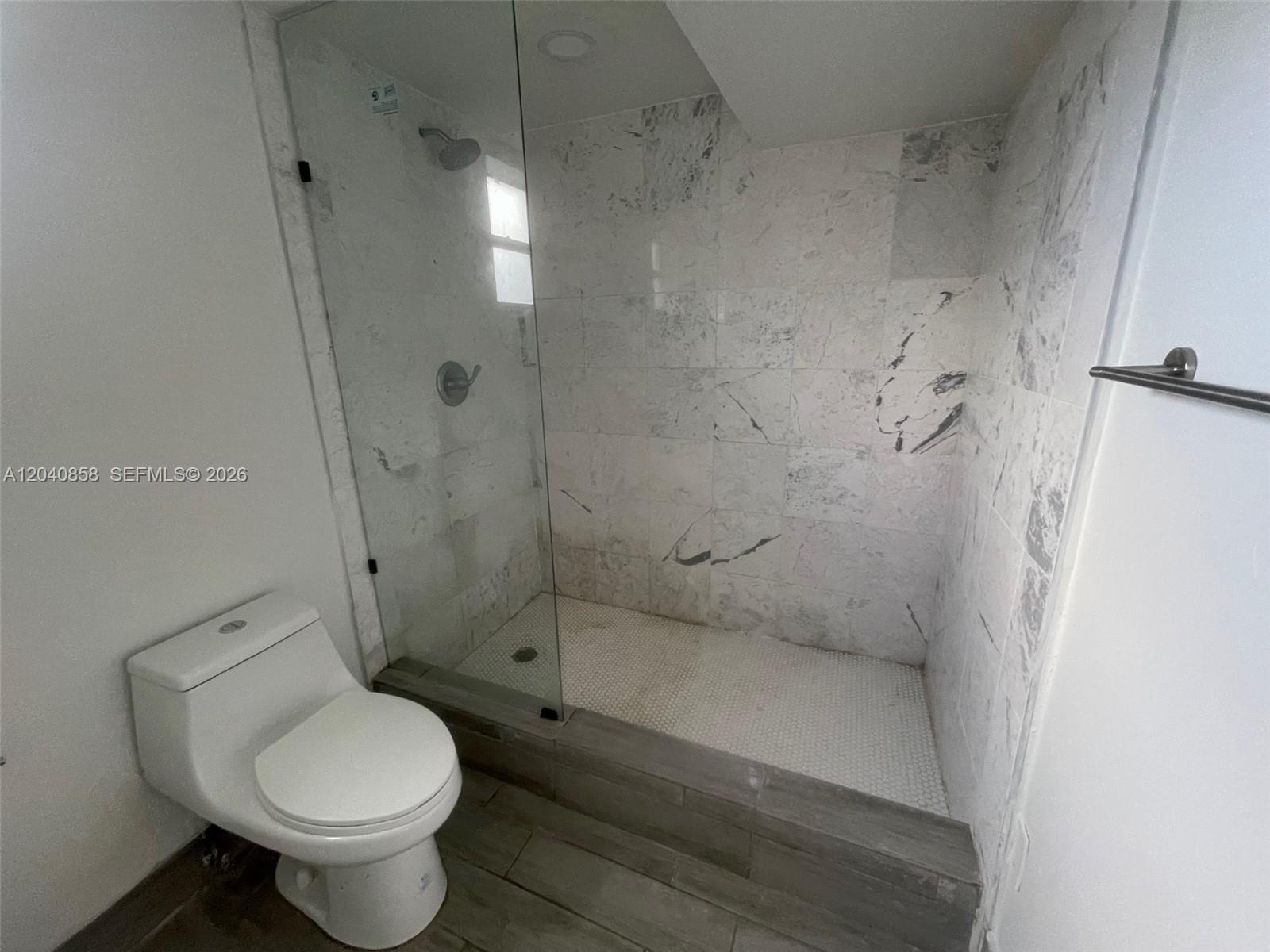 A bathroom features a glass-enclosed shower with marble-style tile walls and a white toilet — 1865 NW 16th St # 1, Miami FL 33125, MIAMI, FL