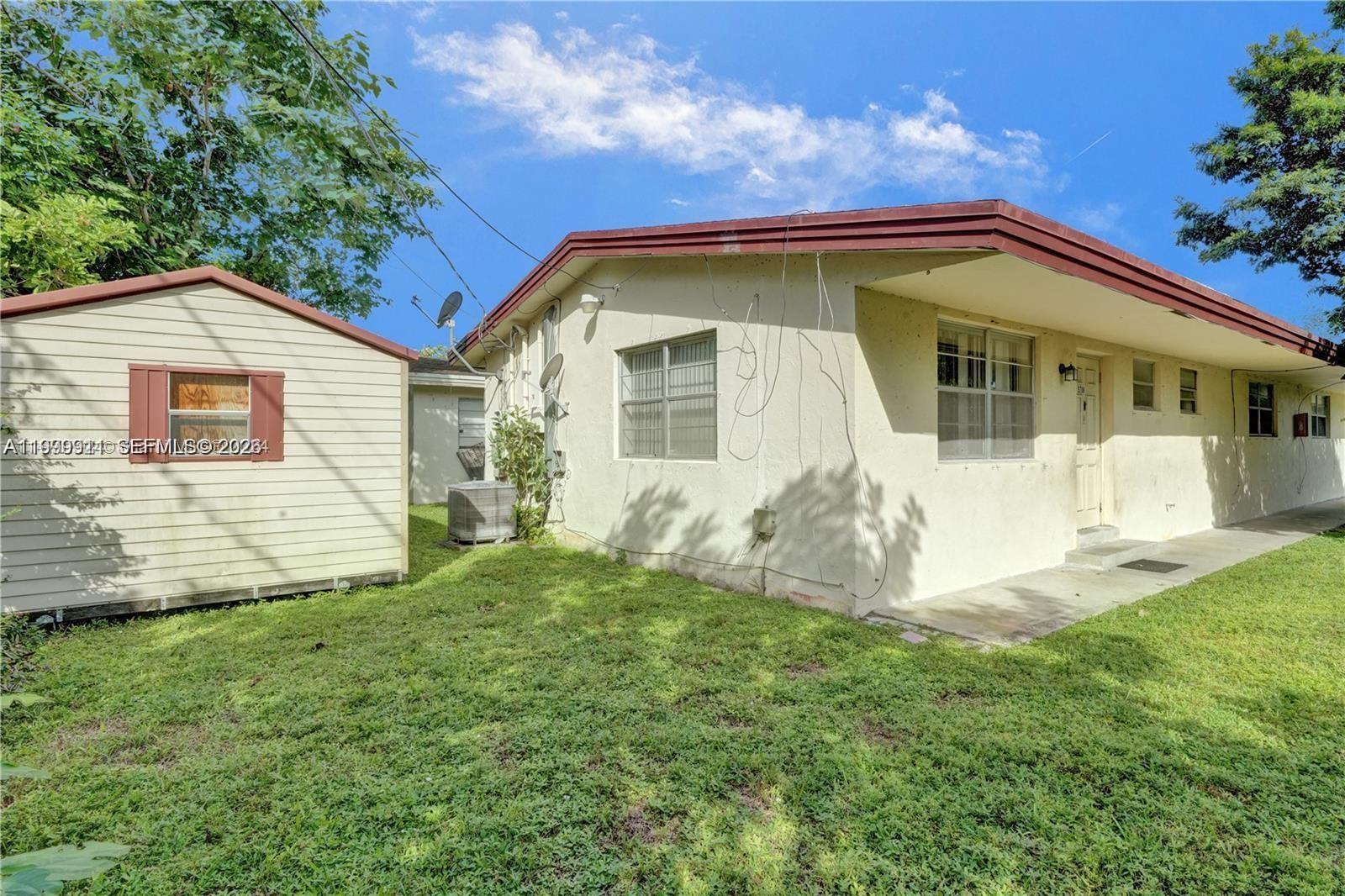 A beige house with a brown roof and an adjacent shed sit on a lawn — 5706 Lincoln St, Hollywood FL 33021, HOLLYWOOD, FL