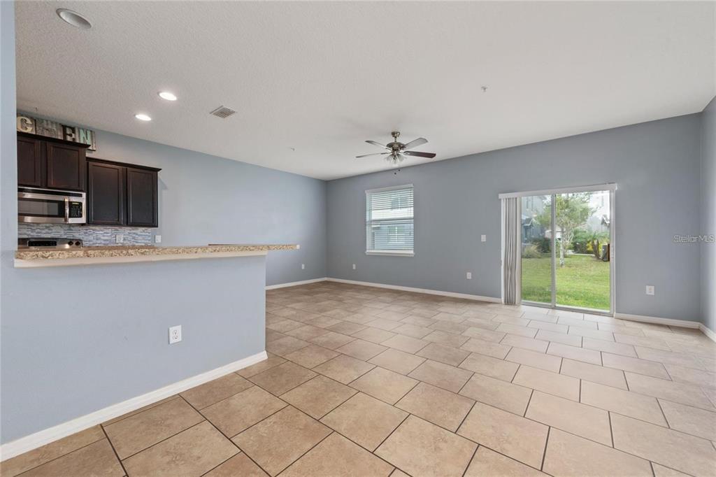 An open-concept living area features light blue walls, tile flooring, a kitchen counter, and sliding doors — 6538 S GOLDENROD ROAD UNIT 68C, ORLANDO, FL