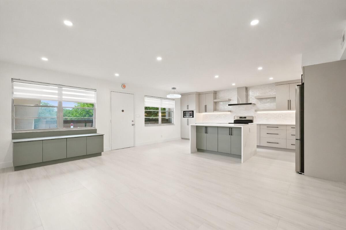 A modern open-concept kitchen and living area with light wood floors and gray cabinetry — 1805 Eleuthera Point # B2, Coconut Creek FL 33066, COCONUT CREEK, FL