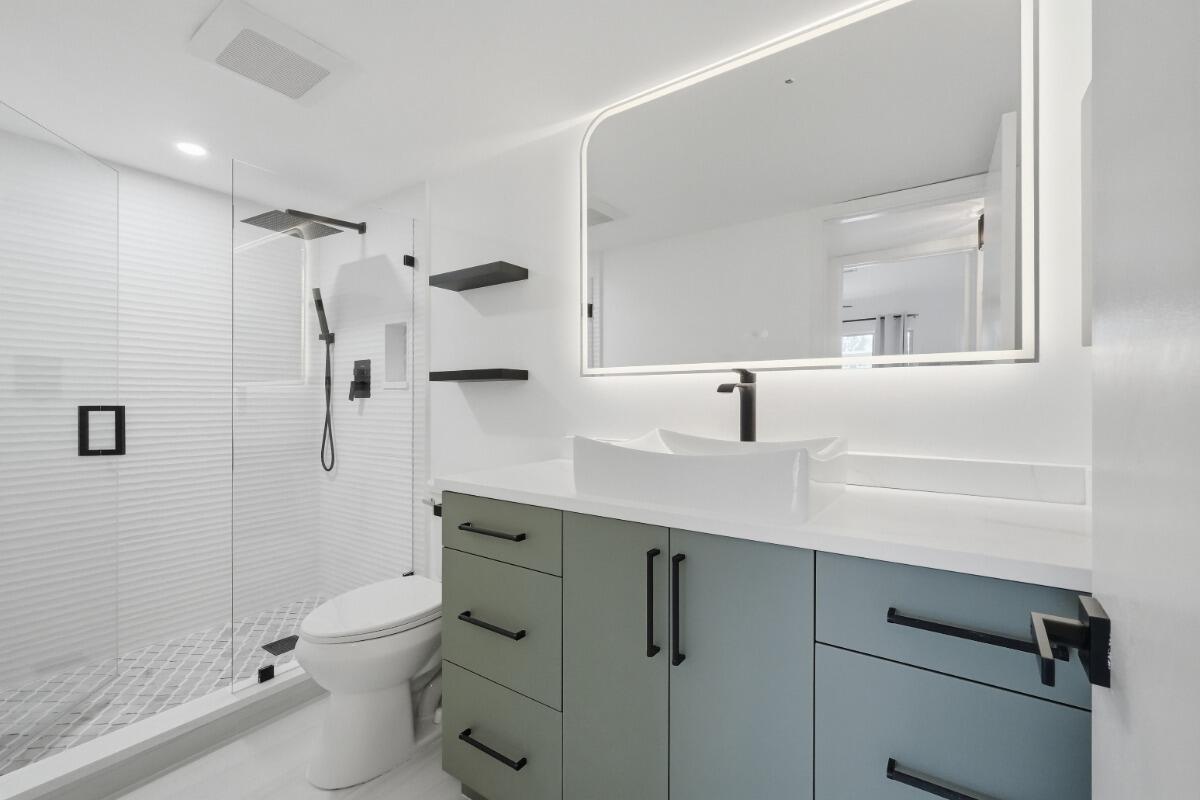 A modern bathroom features a glass-enclosed shower, a multi-colored vanity, and a backlit mirror — 1805 Eleuthera Point # B2, Coconut Creek FL 33066, COCONUT CREEK, FL