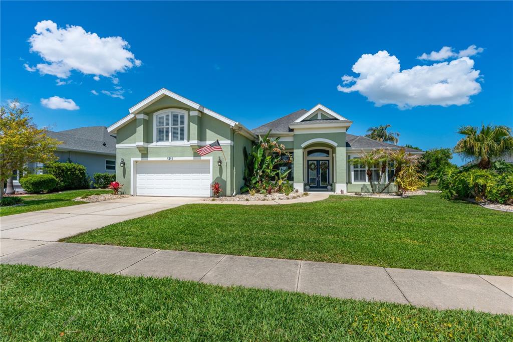 A single-story green house with a white garage and a front lawn under a blue sky — 1311 CREPE MYRTLE LANE, PORT ORANGE, FL