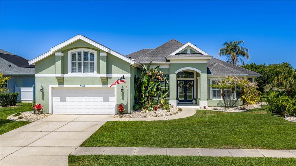 A light green single-story house with a two-car garage and a paved walkway — 1311 CREPE MYRTLE LANE, PORT ORANGE, FL