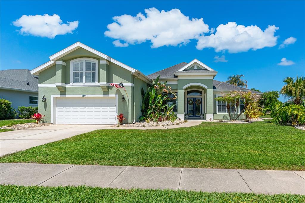 A green single-story house with a two-car garage, arched entryway, and a landscaped front yard — 1311 CREPE MYRTLE LANE, PORT ORANGE, FL