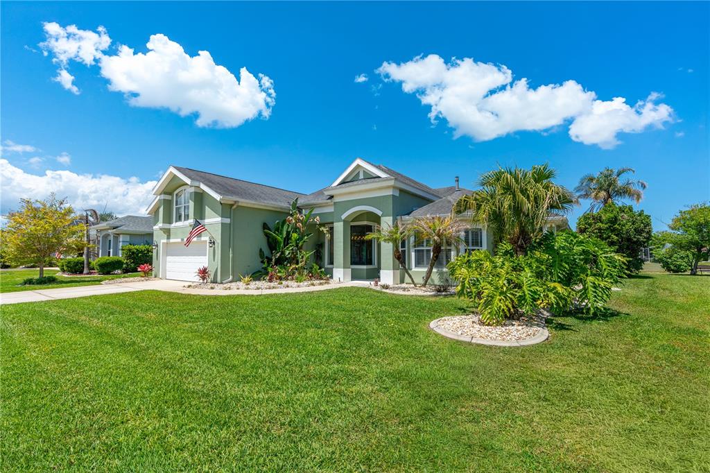 A green single-story house with a white garage and a landscaped front yard — 1311 CREPE MYRTLE LANE, PORT ORANGE, FL