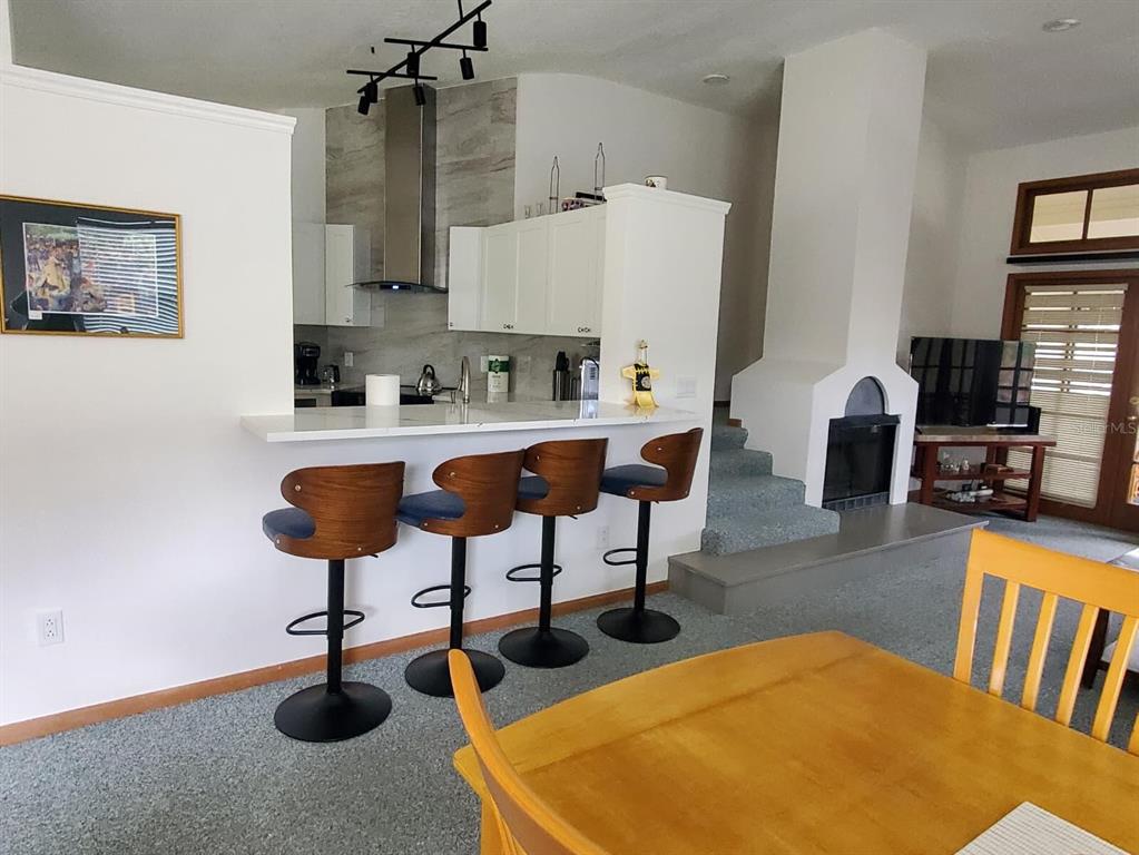 A kitchen with a breakfast bar and stools overlooks a living area with a fireplace — 2924 COTTAGE GROVE COURT UNIT GE, ORLANDO, FL