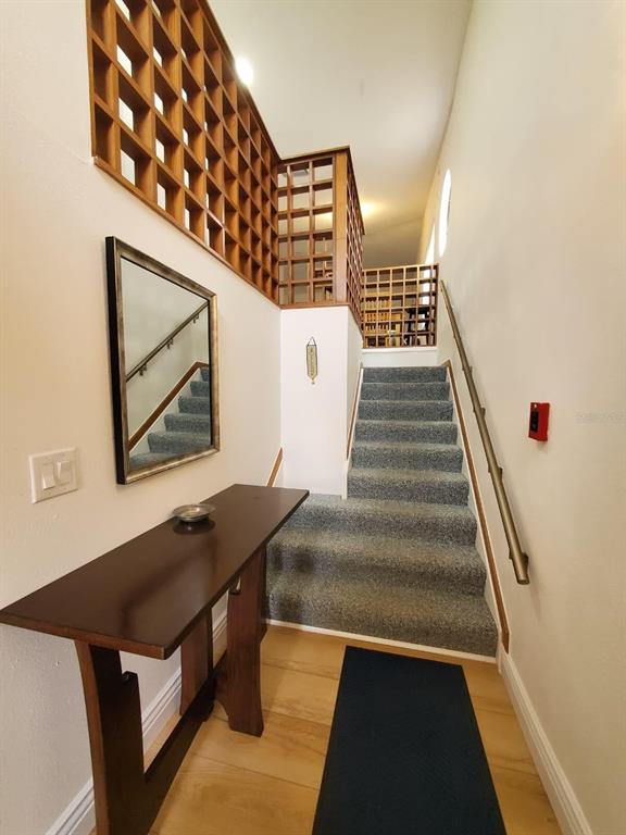 A carpeted staircase leads upward past a wooden room divider and a console table — 2924 COTTAGE GROVE COURT UNIT GE, ORLANDO, FL