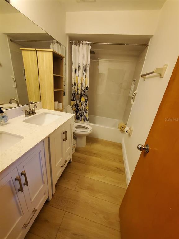 A bathroom features a white vanity, a toilet, and a shower-tub combination with wood-look flooring — 2924 COTTAGE GROVE COURT UNIT GE, ORLANDO, FL