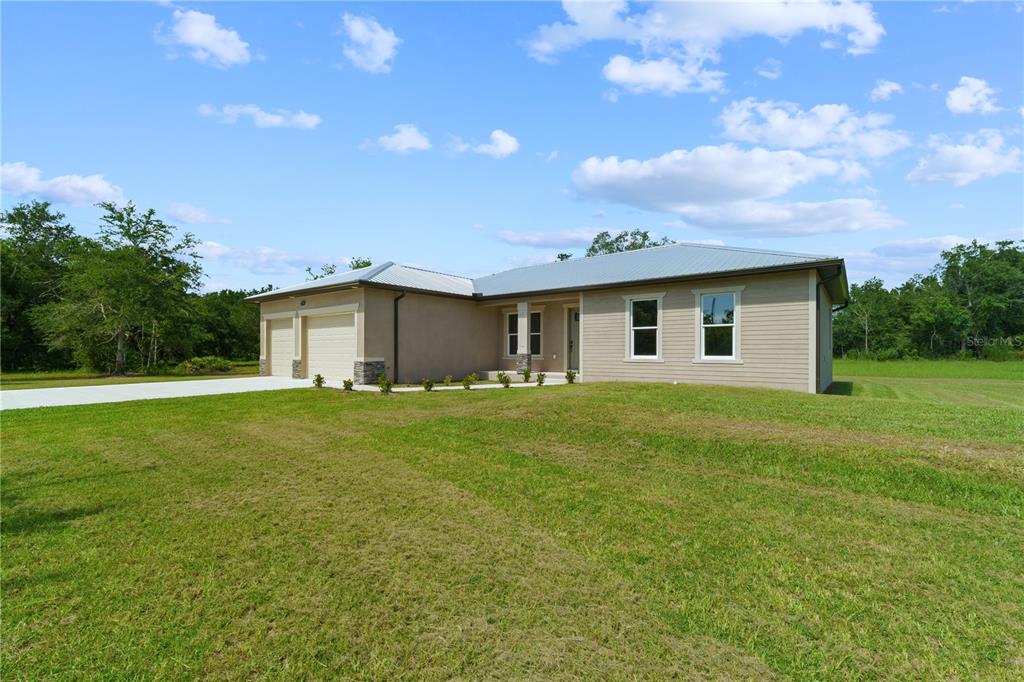 A single-story house with a two-car garage and light-colored siding sits on a grassy lot — 1201 NE CHILDRESS AVENUE, ARCADIA, FL