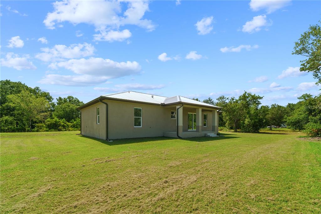 A tan, single-story house with a metal roof sits on a large, grassy lot — 1201 NE CHILDRESS AVENUE, ARCADIA, FL
