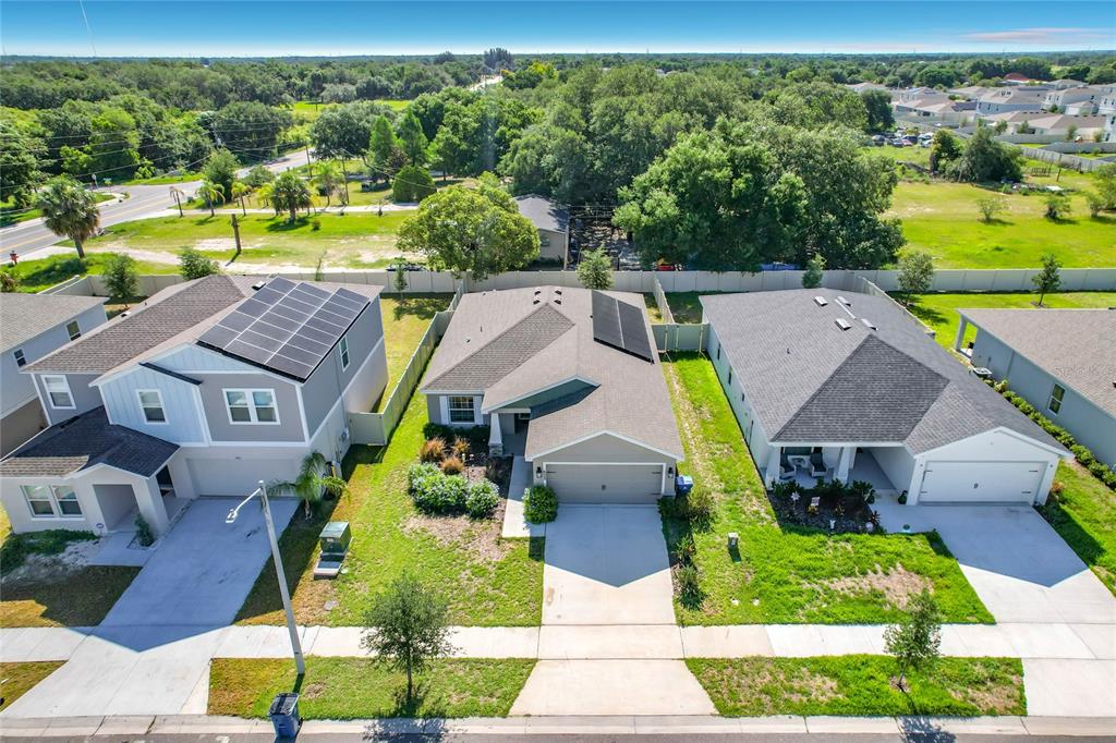 An aerial view shows three suburban houses with driveways and solar panels on their roofs — 609 AMBLESIDE DRIVE, HAINES CITY, FL