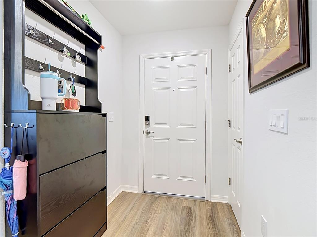 An entryway features a black storage unit, a white front door, and wood-look flooring — 609 AMBLESIDE DRIVE, HAINES CITY, FL