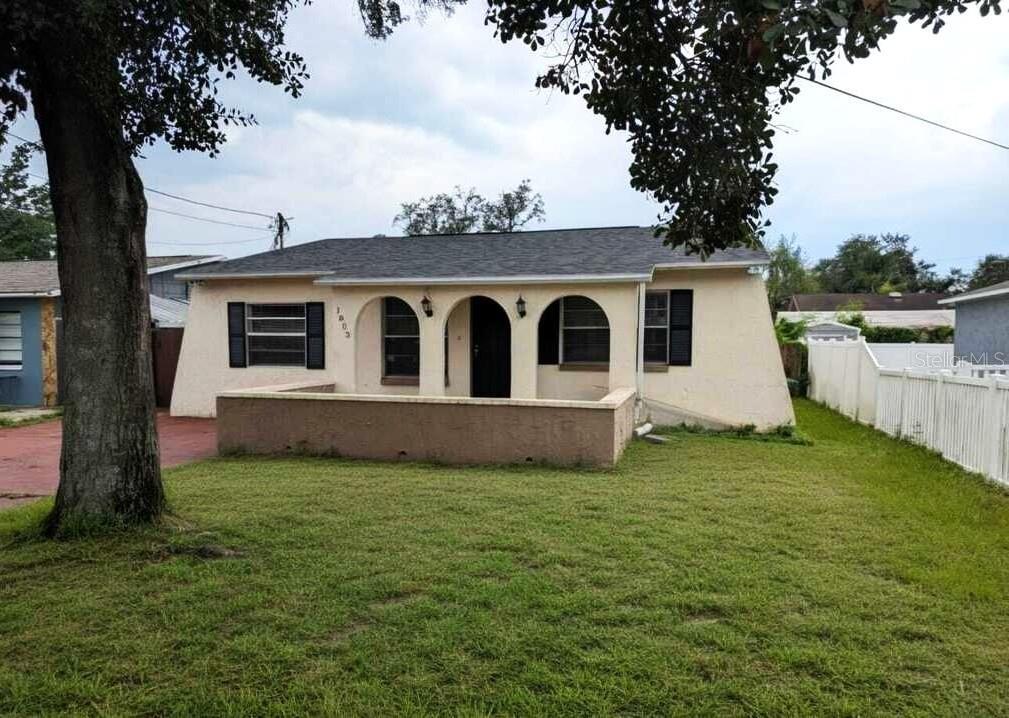 A single-story house with a stucco exterior, arched porch openings, and a front lawn — 1803 E HUMPHREY STREET, TAMPA, FL