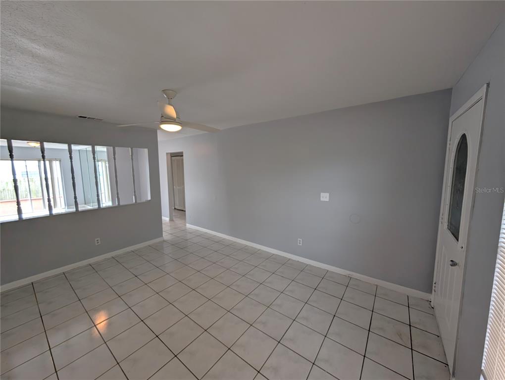 An empty room with light gray walls, white tile flooring, and a ceiling fan — 1803 E HUMPHREY STREET, TAMPA, FL