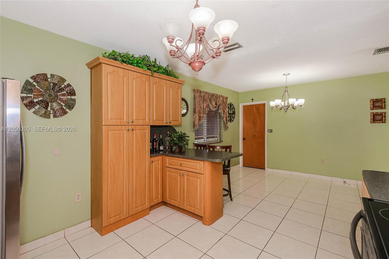 A kitchen features light wood cabinetry, a small breakfast bar, and light green walls — 271 E 17th St, Hialeah FL 33010, HIALEAH, FL