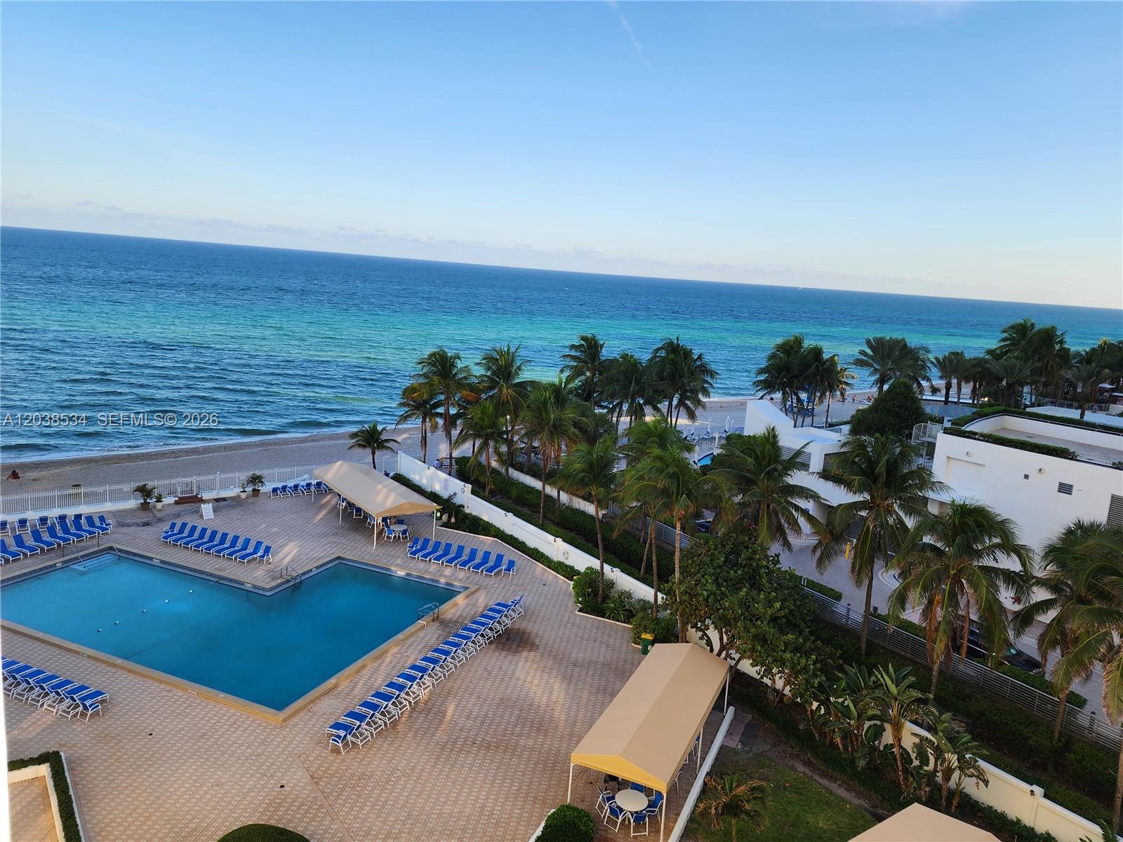 An aerial view shows a swimming pool, lounge chairs, palm trees, and the ocean — 3505 S Ocean Dr # 716, Hollywood FL 33019, HOLLYWOOD, FL