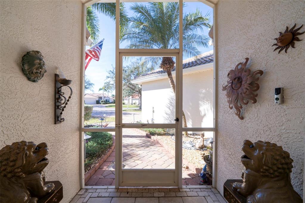 A view from a covered entryway looking out through a screen door toward a neighborhood street — 4115 CAPE COLE BOULEVARD, PUNTA GORDA, FL