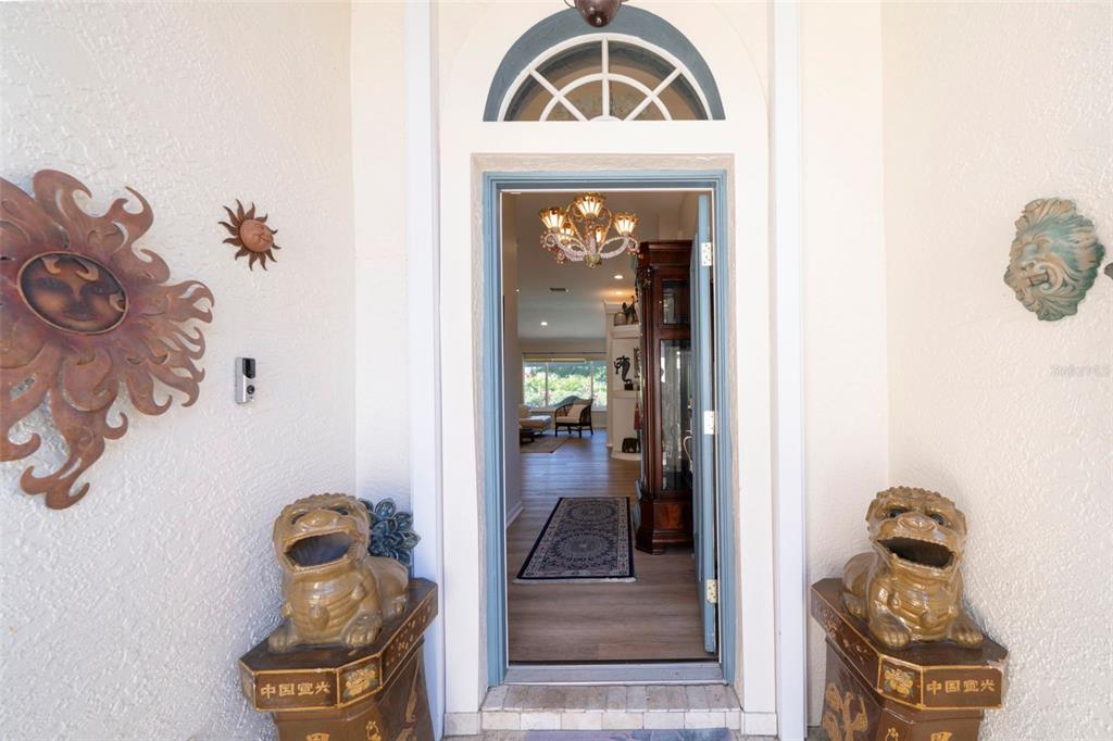 The front entrance features a doorway flanked by two stone lion statues and wall decor — 4115 CAPE COLE BOULEVARD, PUNTA GORDA, FL