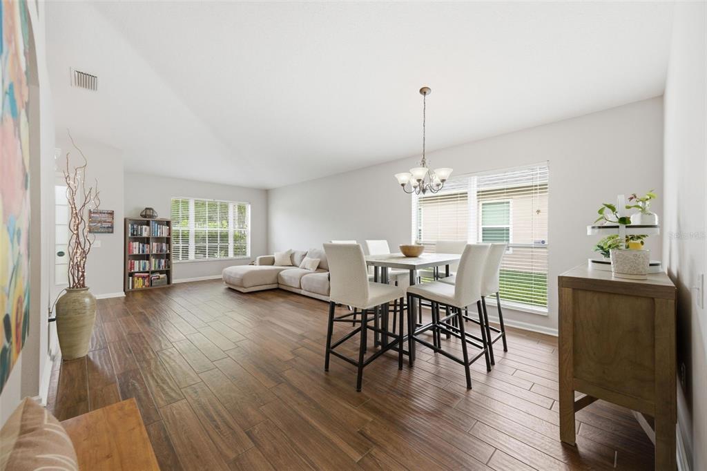 A dining area and living room with wood-look tile flooring and a high ceiling — 25114 LEXINGTON OAKS BOULEVARD, WESLEY CHAPEL, FL
