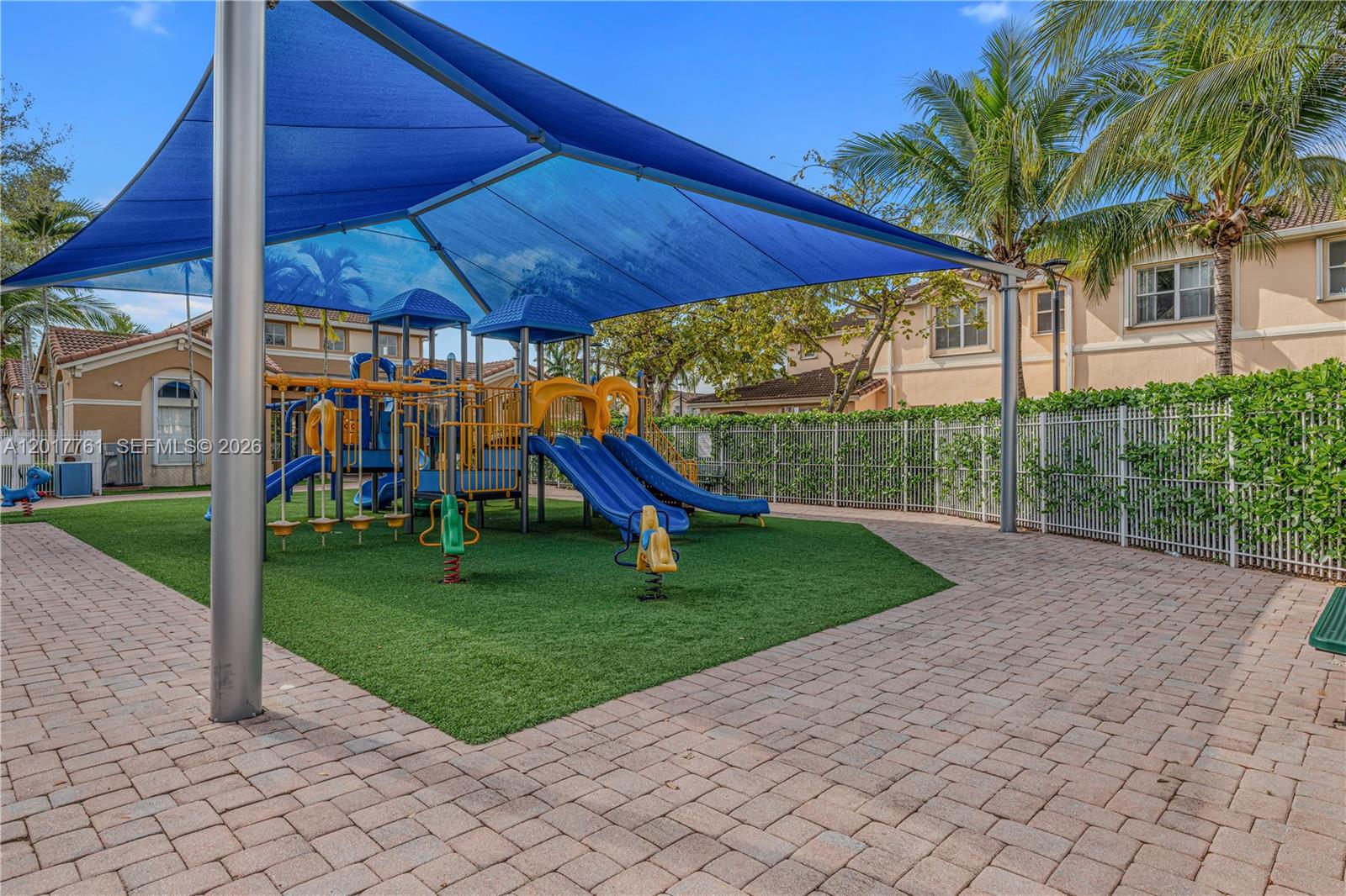 A playground with a blue shade canopy, slides, and climbing equipment sits on artificial turf — 12172 SW 124th Path, Miami FL 33186, MIAMI, FL