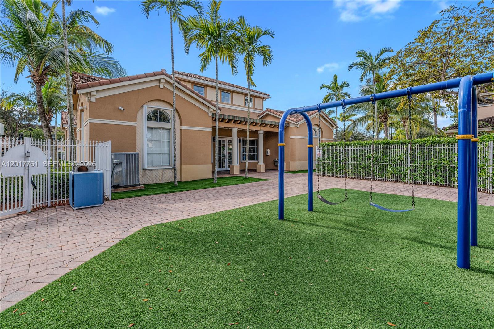 An outdoor playground area with a swing set sits on artificial turf beside a building — 12172 SW 124th Path, Miami FL 33186, MIAMI, FL
