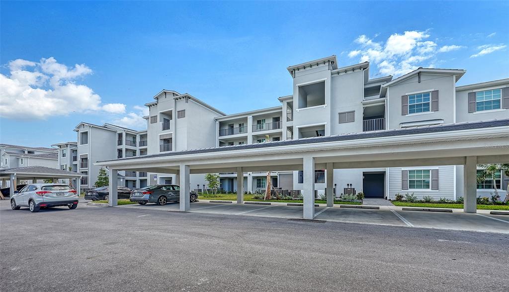 A multi-story apartment building with a covered parking structure in the foreground — 17600 OPAL SAND DRIVE UNIT 301, VENICE, FL