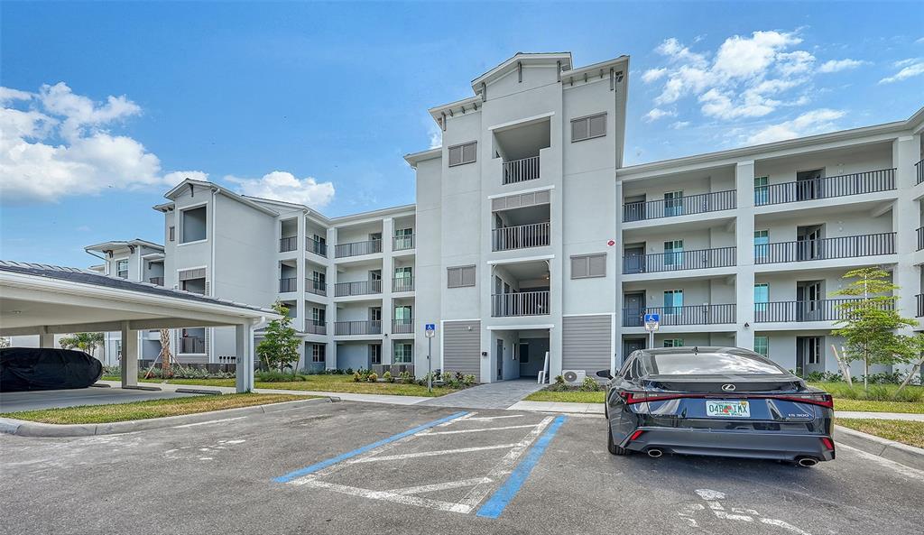A multi-story apartment building exterior with a parking lot and a covered carport — 17600 OPAL SAND DRIVE UNIT 301, VENICE, FL