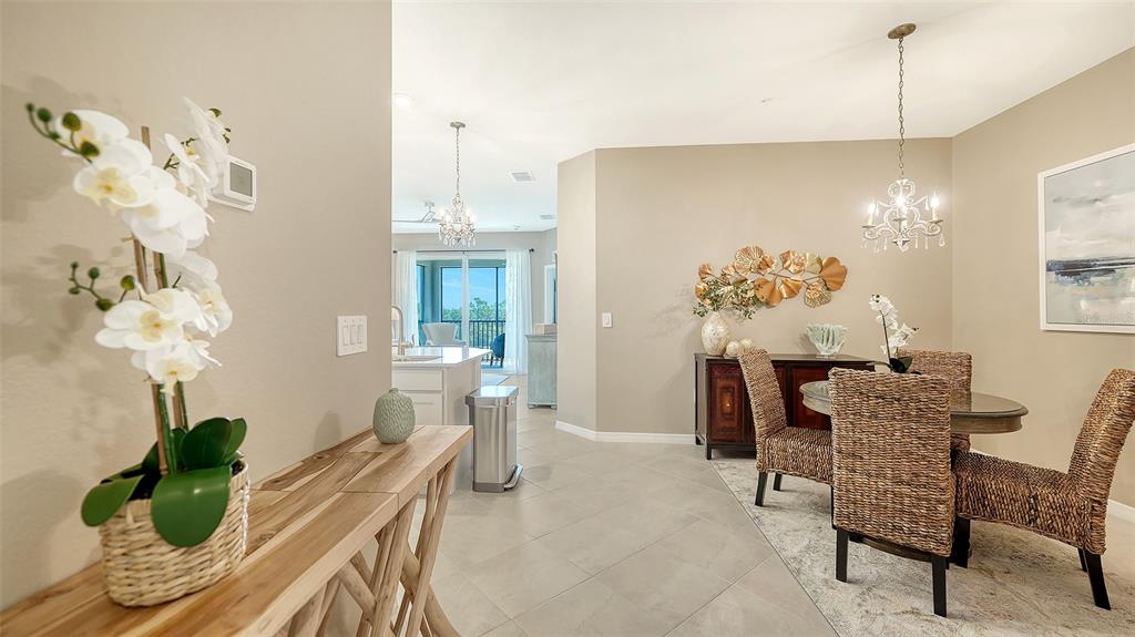 A dining area with a round table and woven chairs leads to a kitchen beyond — 17600 OPAL SAND DRIVE UNIT 301, VENICE, FL